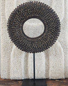 Schelpenketting bruin L op zwarte metalen standaard met donkerbruine kauri-schelpen en gevlochten jute band op een witte achtergrond