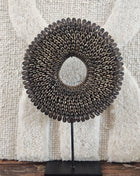 Schelpenketting bruin M op zwarte metalen standaard met bruine kauri-schelpen en gevlochten jute band op een witte achtergrond