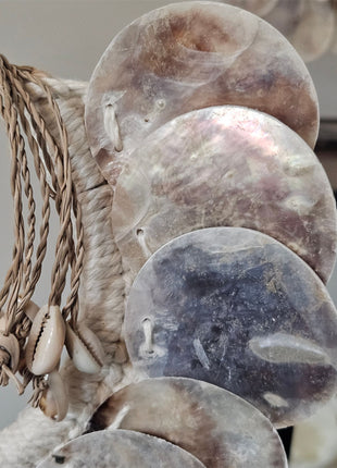 Close-up van schelpenketting parelmoer met ronde glanzende parelmoerschijfjes en kauri-schelpen op een witte achtergrond