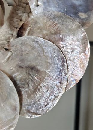 Close-up van ronde parelmoerschijfjes en kauri-schelpen van schelpenketting parelmoer op een witte achtergrond