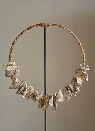 Schelpenketting op standaard Placuna als ring opgehangen op een naturel houten standaard