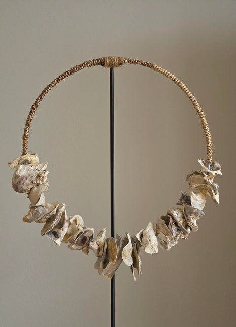 Schelpenketting op standaard Placuna als ring opgehangen op een naturel houten standaard