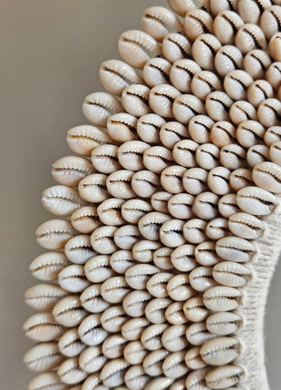 Close-up van schelpenketting wit-beige L met dicht opeengepakte kauri-schelpen en gevlochten jute band