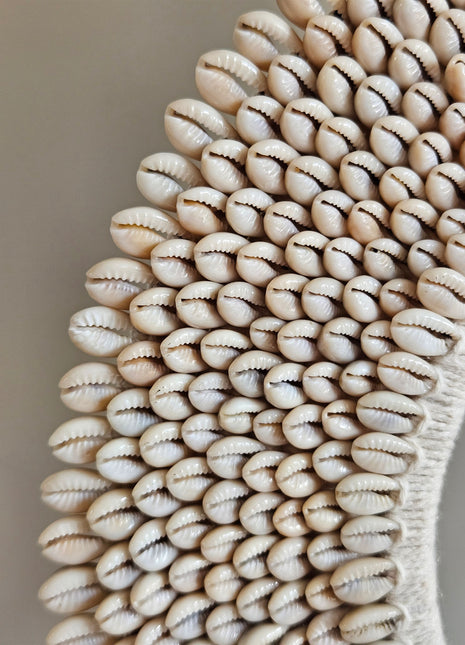 Close-up van schelpenketting wit-beige L met dicht opeengepakte kauri-schelpen en gevlochten jute band