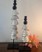 Ornament schelpentoren pearl naturel L op zwarte metalen standaard met gestapelde parelmoer schijfschelpen en drie zwarte houten bollen op een witte achtergrond