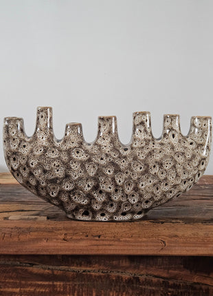 Tulpenvaas speckled crème aardewerk H 15.5 cm met zeven kleine halsopeningen op een houten tafel voor een lichtgrijze muur