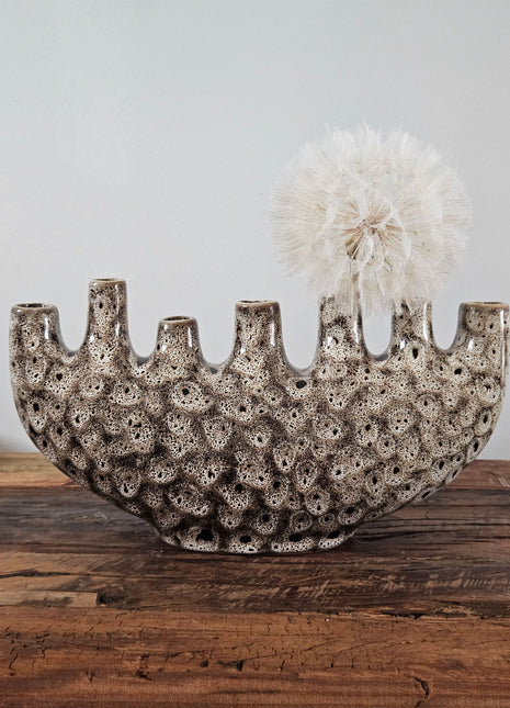 Tulpenvaas speckled crème aardewerk H 15.5 cm met zeven kleine halsopeningen en een halfronde boogvorm op een houten ondergrond voor een lichtgrijze muur