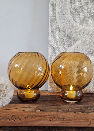 Vaas amber glas Ø17 x H20 cm naast een glazen vaas bruin amber glanzend L op een witte ondergrond