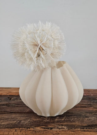 Vaas beige glas Ø 14 x H 11 cm met bolle ribbel-structuur en een crème dandelion kunsttak op een houten ondergrond voor een lichtgrijze muur