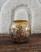Bolvaas goud metaal M met ruwe gegraveerde buitenkant en goudkleurige binnenkant op een houten ondergrond voor een wit linnen wandpaneel