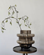 Vaas Disk donkerbruin glas gepresenteerd op dressoir met droogbloemen