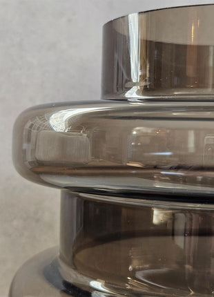 Vaas Disk donkerbruin glas met warme gloed in interieur setting