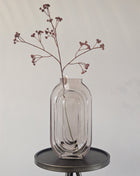 Vaas grijs zalm glas met elegante vorm en kleurverloop hoogte 30 cm getoond op een bijzettafel met kleurrijke bloemen.
