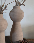 Vooraanzicht van taupe Marconne vaas met ruwe afwerking en beige kunstbloemen naast lotus op een houten dienblad