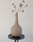 Vaas stone-look oker metaal met organische vorm en natuurlijke afwerking hoogte 35 cm getoond op een bijzettafel. De vaas heeft kleurrijke bloemen.