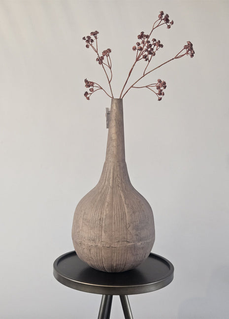 Vaas stone-look oker metaal met organische vorm en natuurlijke afwerking hoogte 35 cm getoond op een bijzettafel. De vaas heeft kleurrijke bloemen.