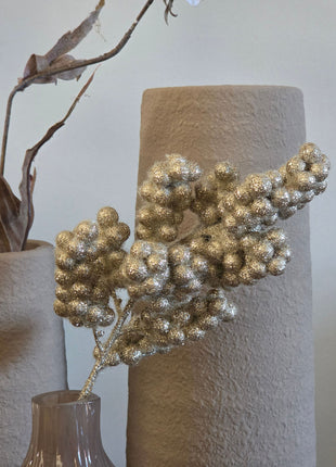 Close-up van goudkleurige glitterbessen in taupe-bruine Velin vaas met glanzende afwerking voor beige vazen