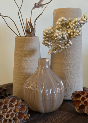 Vooraanzicht van taupe-bruine Velin vaas met glanzende ribbels naast beige vazen en lotus op een houten dienblad