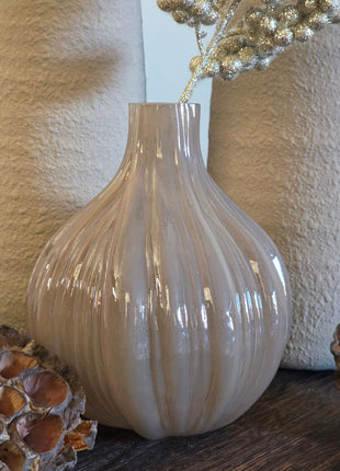 Vooraanzicht van taupe-bruine Velin vaas met glanzende ribbels en goudkleurige kunsttak naast lotus op hout