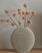 Vaas Ovaal Bubio M van Light & Living in champagne met een pompom bloem op een houten ondergrond