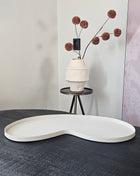 Vase the World Dienblad Villeta M Ivory metaal met organische vorm op dressoir met bruine pompom zijdetak op de achtergrond