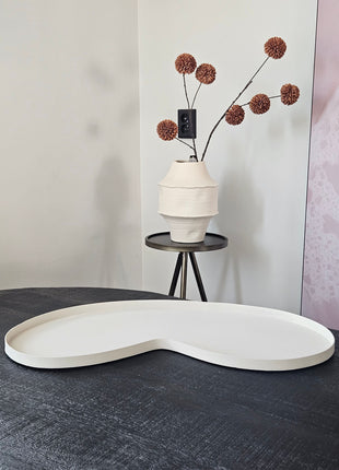 Vase the World Dienblad Villeta M Ivory metaal met organische vorm op dressoir met bruine pompom zijdetak op de achtergrond