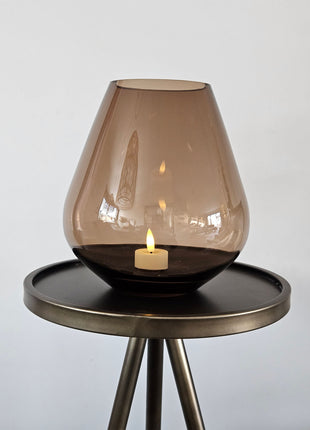 Vase the World vaas Tasman S+ taupe Ø20 x H22 cm met druppelvorm en mondgeblazen glanzend taupe glas op een donker bijzettafeltje