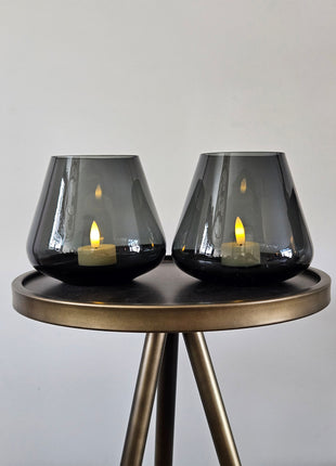 Set van twee Vase the World waxinelichthouders Tasman XS grey op een sidetable met een brandende kaars