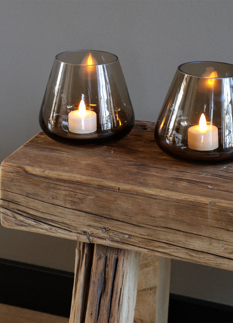 Vase the World waxinelichthouder Tasman in een prachtige Taupe kleur. De waxinelichthouder is gemaakt van glas en is mondgeblazen. Sfeerfoto van een set op een houten bijzet bankje