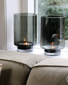 Vase the World waxinelichthouder Thames in een prachtige grijze kleur. De waxinelichthouder is gemaakt van glas en is mondgeblazen. Afgebeeld als een set van twee in een vensterbank hoge conische vorm.