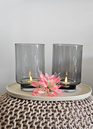 Set van twee Vase the World waxinelichthouders Thames XS grey in hoge conische vorm met brandende LED-kaars op een witte ondergrond