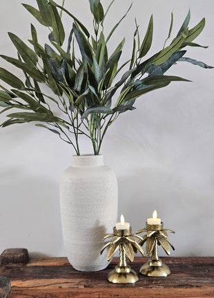 Waxinelichthouder Palmboom goud aluminium op een styling oppervlak met een brandende kaars