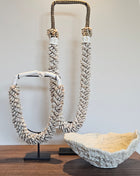 Interieur Set Coral met een Light en Living koraal ornament in crème en twee beige schelpenkettingen op standaard.