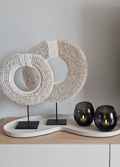 Woonaccessoire Set Ivory Class met twee wit-beige schelpenkettingen en twee grijze Moho waxinelichthouders op een ivoorkleurig dienblad.