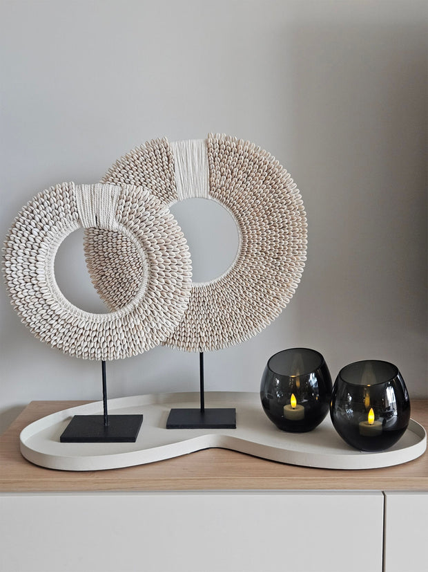 Woonaccessoire Set Ivory Class met twee wit-beige schelpenkettingen en twee grijze Moho waxinelichthouders op een ivoorkleurig dienblad.