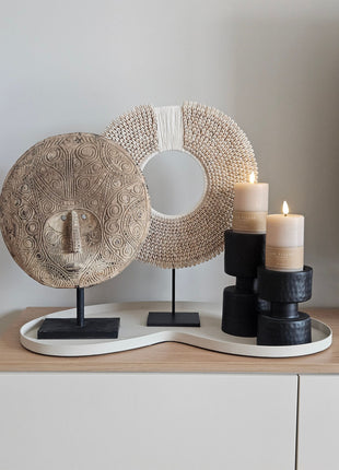 Decoratie Set Ivory Flow met een naturel masker op voet, wit-beige schelpenketting en twee zwarte kandelaars op ivoor dienblad.