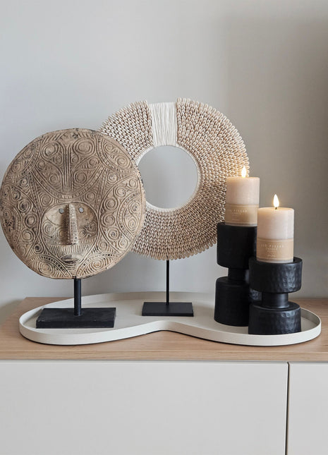 Decoratie Set Ivory Flow met een naturel masker op voet, wit-beige schelpenketting en twee zwarte kandelaars op ivoor dienblad.