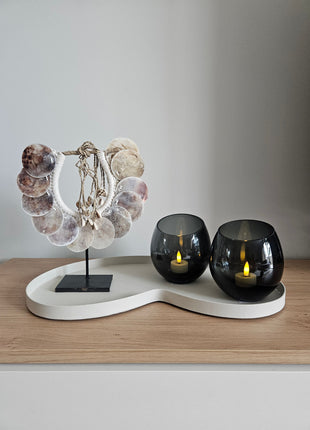 Woonaccessoire Set Ivory Parelmoer met een parelmoer schelpenketting en twee grijze Moho waxinelichthouders op een ivoorkleurig dienblad.