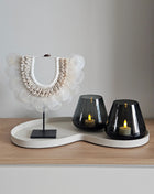 Woonaccessoire Set Ivory Sand met een witte schelpenketting op standaard en twee grijze Tasman waxinelichthouders op een ivoor dienblad.