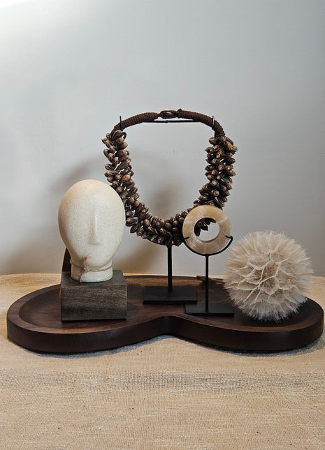 Woonaccessoire Set Walnut Comfort met een houten hoofd ornament, onyx schijf, paardenbloem en bruine schelpenketting op walnoot dienblad.