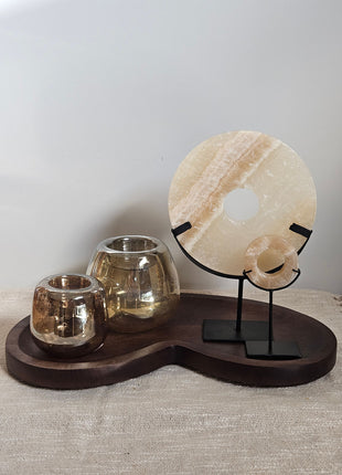 Woonaccessoire Set Walnut Onyx met twee beige onyx ornamenten en twee bruingrijze Capira waxinelichthouders op een walnoot dienblad.