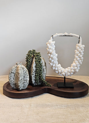 Decoratie Set Walnut Vase met twee keramieke Arquette vaasjes, een groene kunst erwtenplant en een witte schelpenketting op walnoot dienblad.